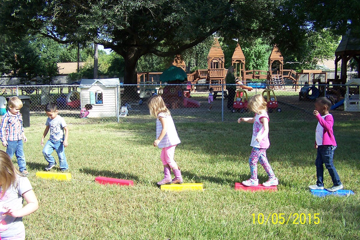 Children playing on balance boards in a grassy area