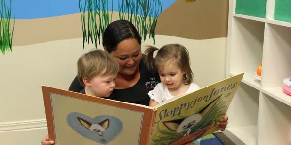 Person reading a book to two children