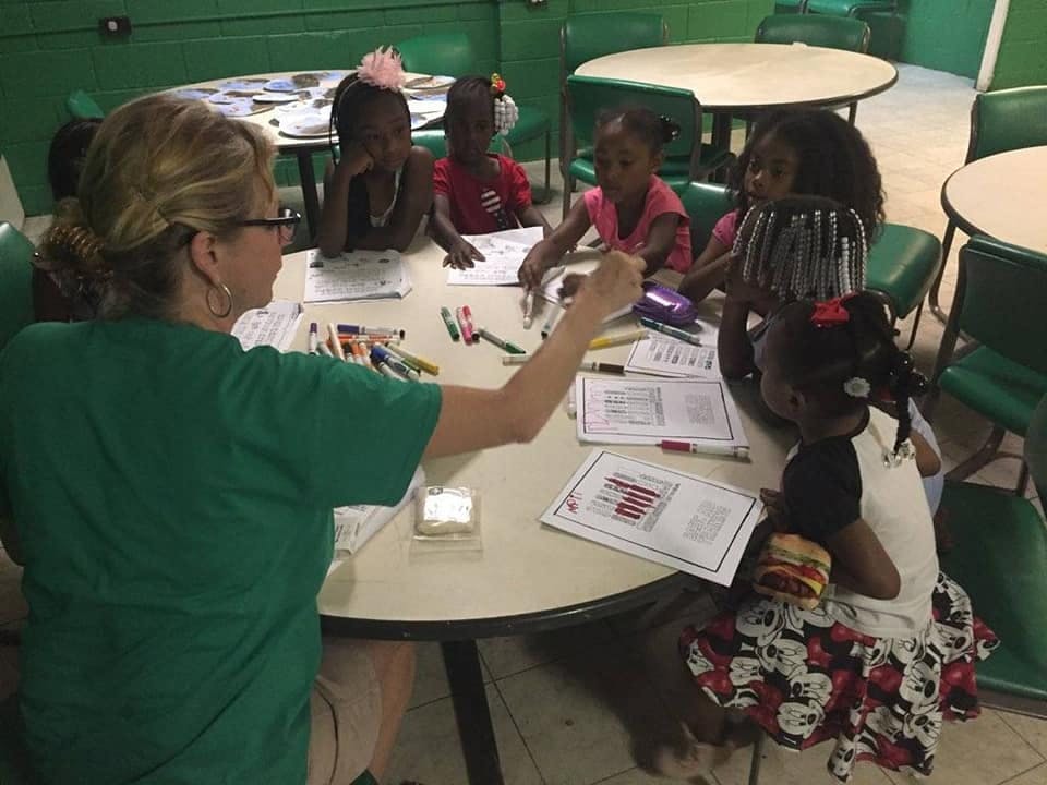Adult and children sitting at a table with papers and markers