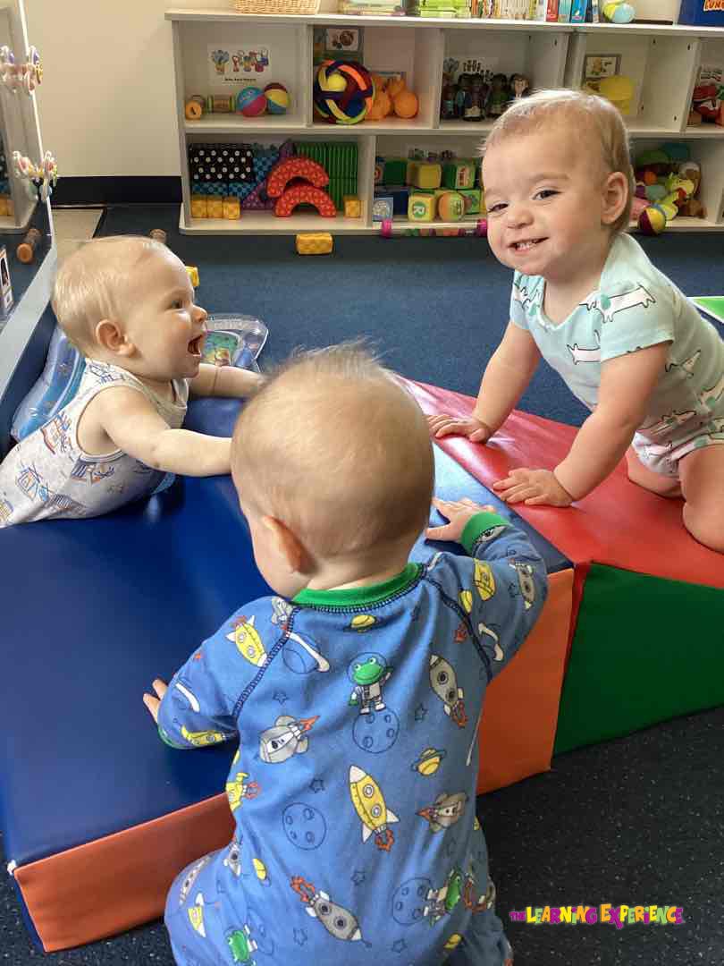 Three babies playing on soft play mats