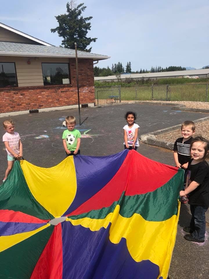 Children holding a colorful parachute outdoors