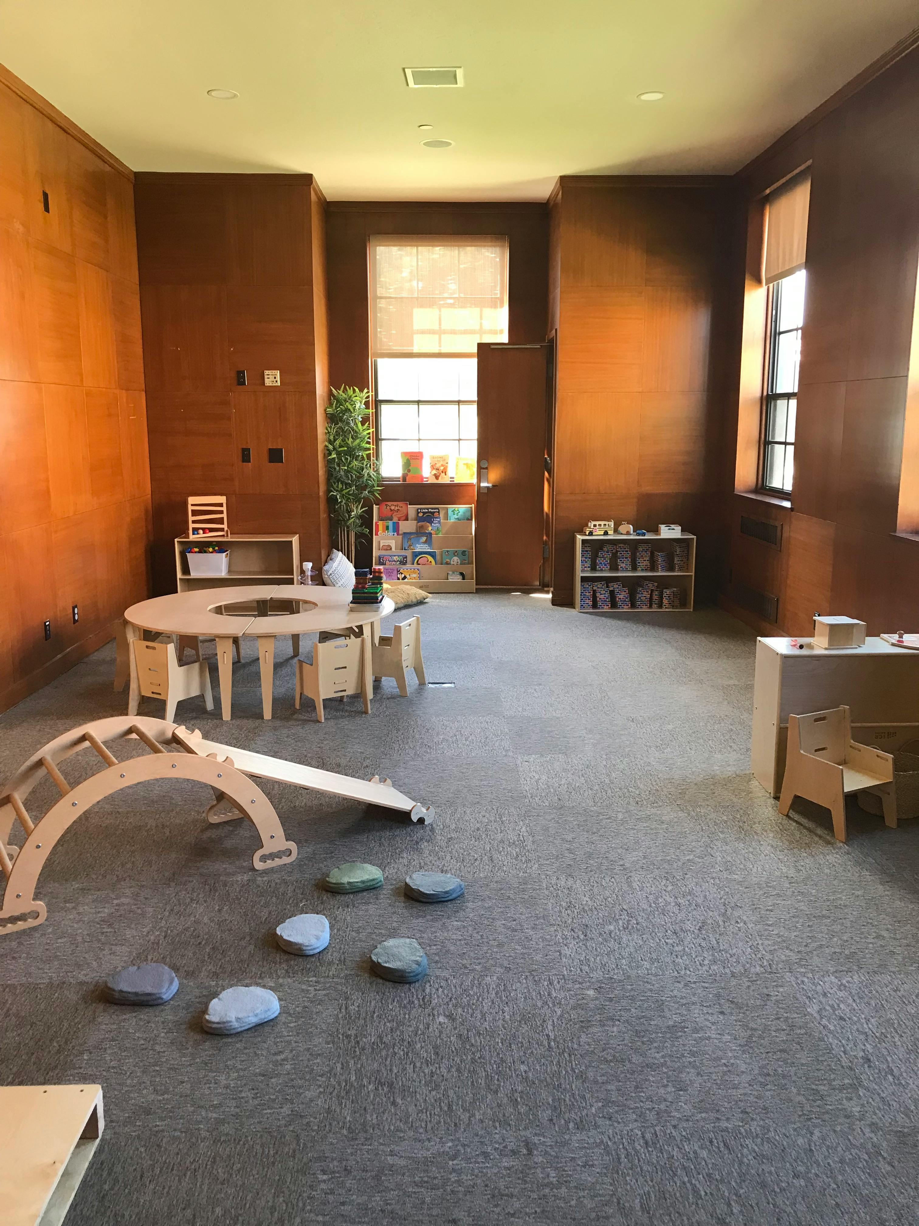 Empty classroom with wooden furniture and play equipment