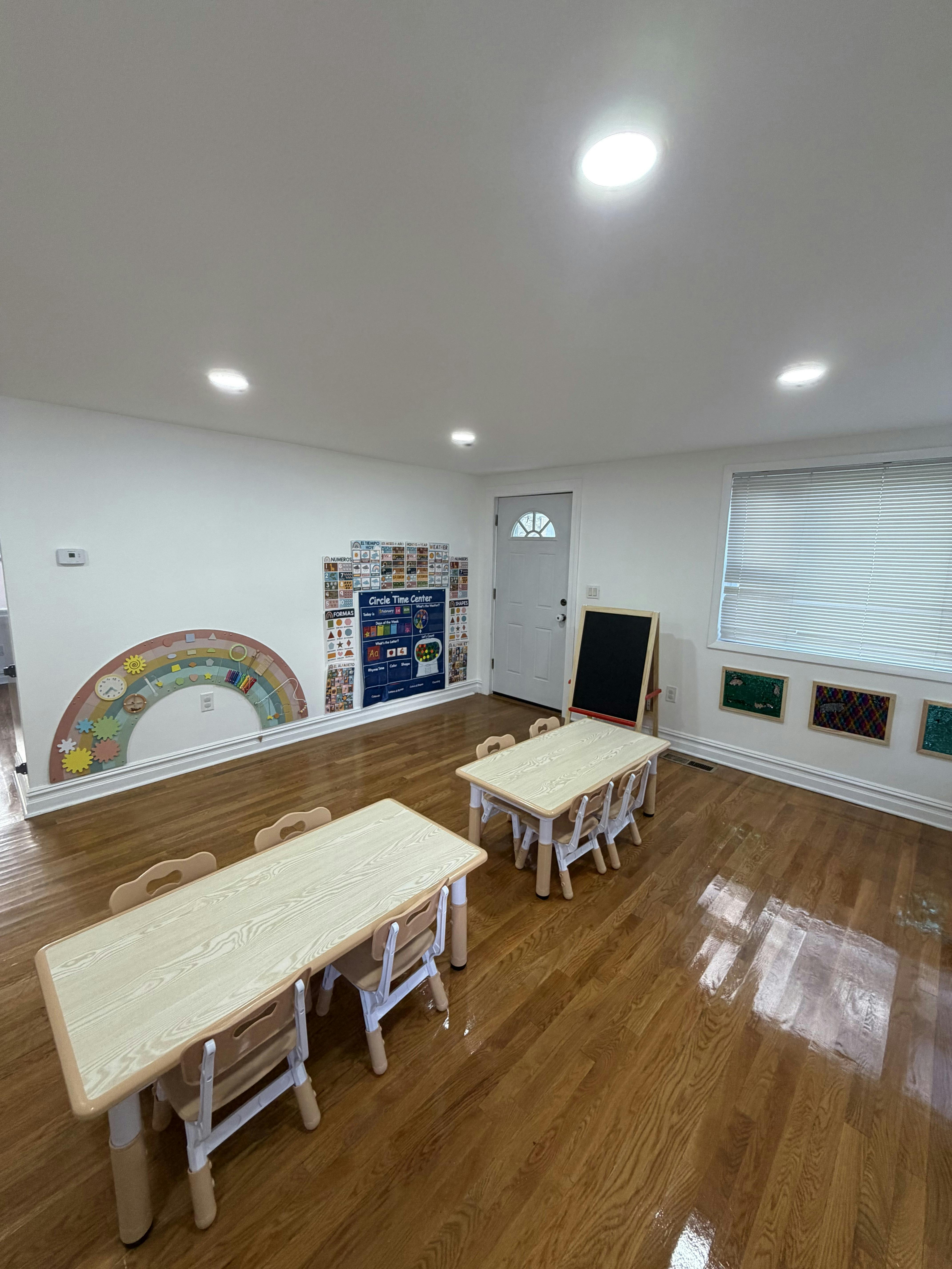 Classroom with small tables and chairs, a chalkboard, and educational posters
