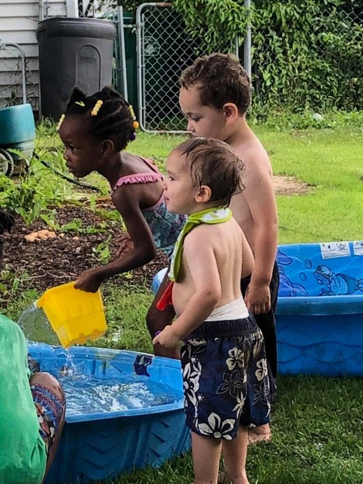 Three children playing with water in a yard