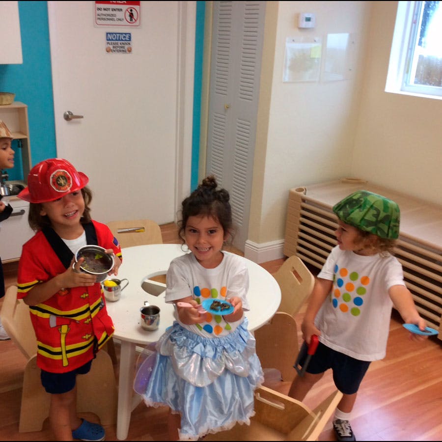 Three children playing dress-up in a classroom