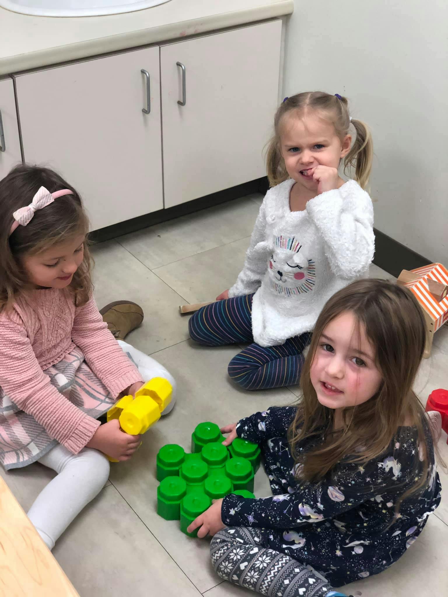 Three children playing with building blocks on the floor