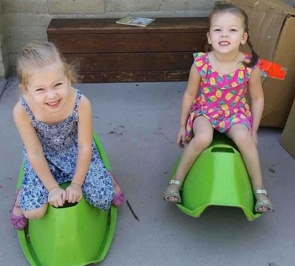 Two children sitting on green rocking toys