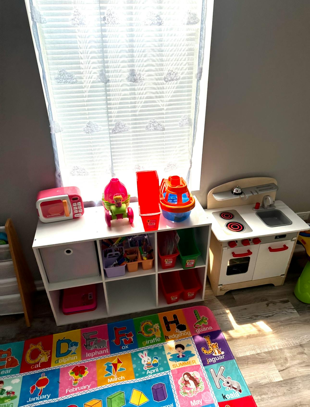 Play kitchen and toy storage unit with colorful rug