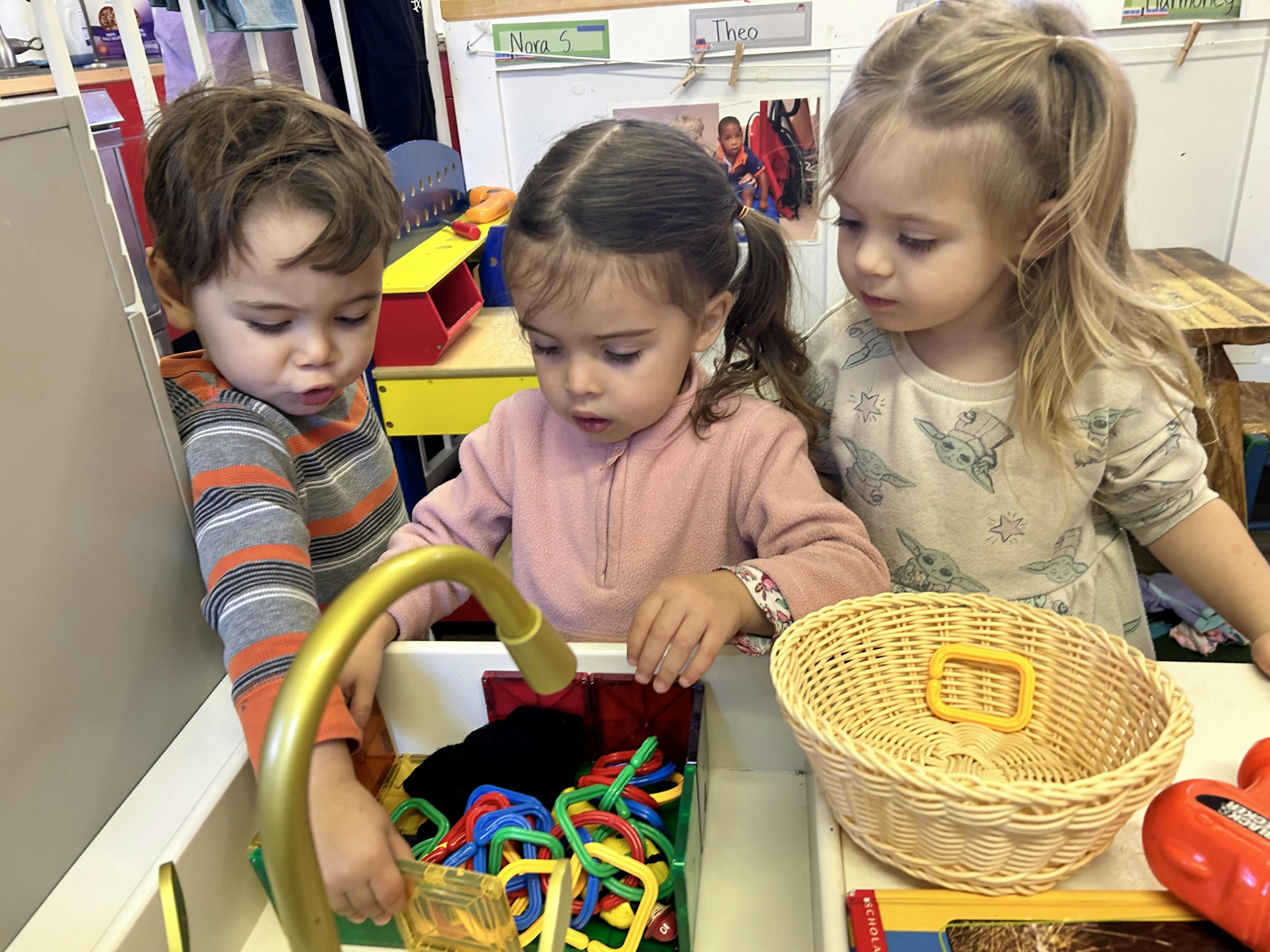 Three children playing with toys in a classroom