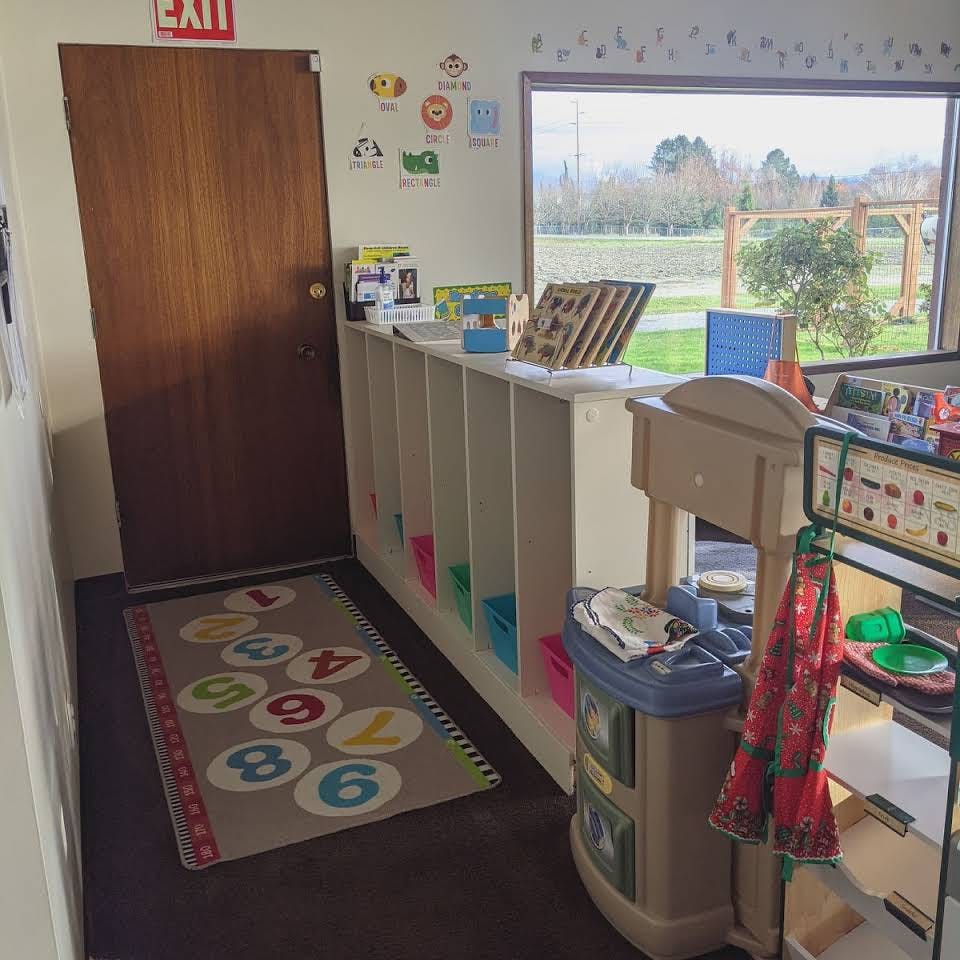 Classroom with cubbies, play kitchen, and window overlooking outdoors