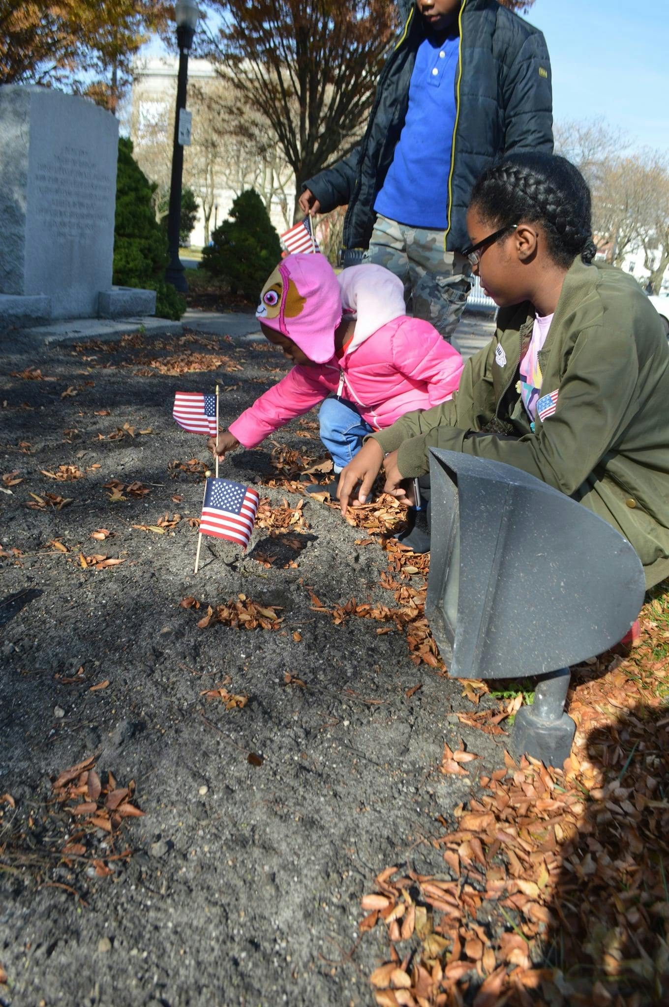 Three children placing small American flags in the ground