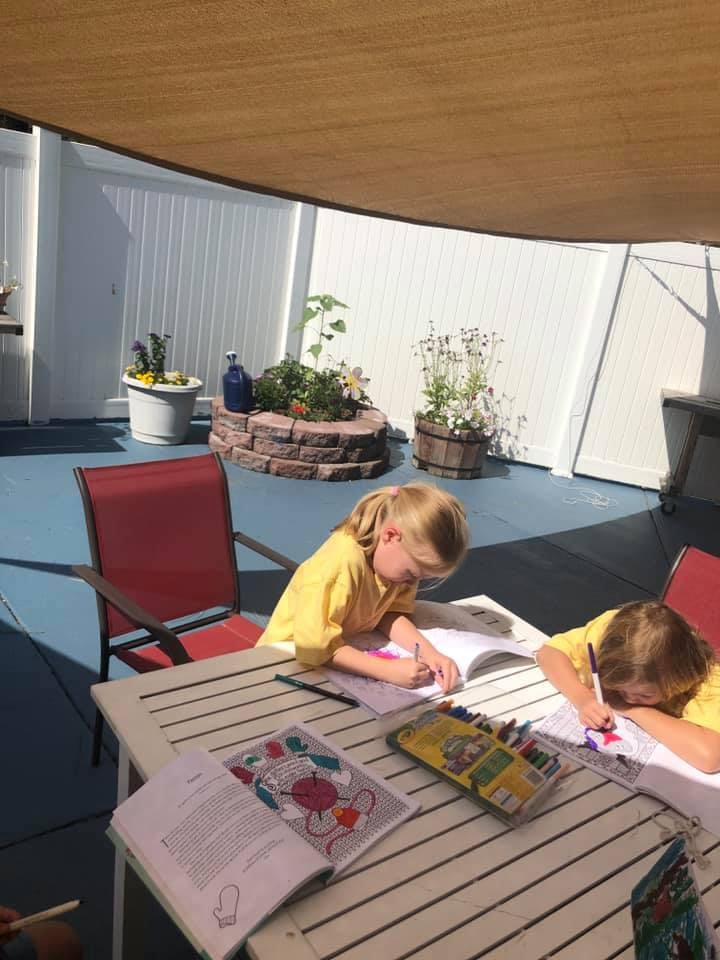 Two children drawing at a table outdoors