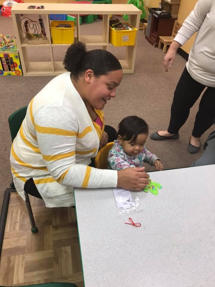 Person and child at a table with small objects