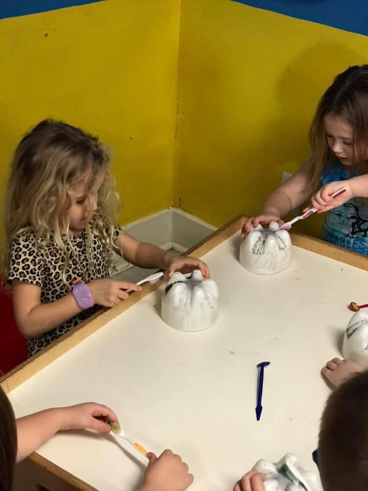 Children brushing teeth on plastic bottle models