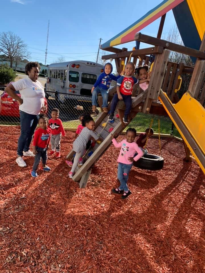 Adult supervising children playing on a playground structure