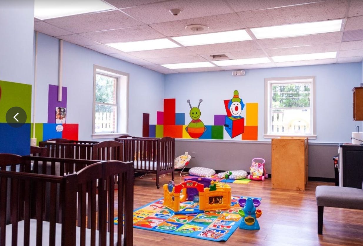 Nursery room with cribs, colorful blocks, and play mats