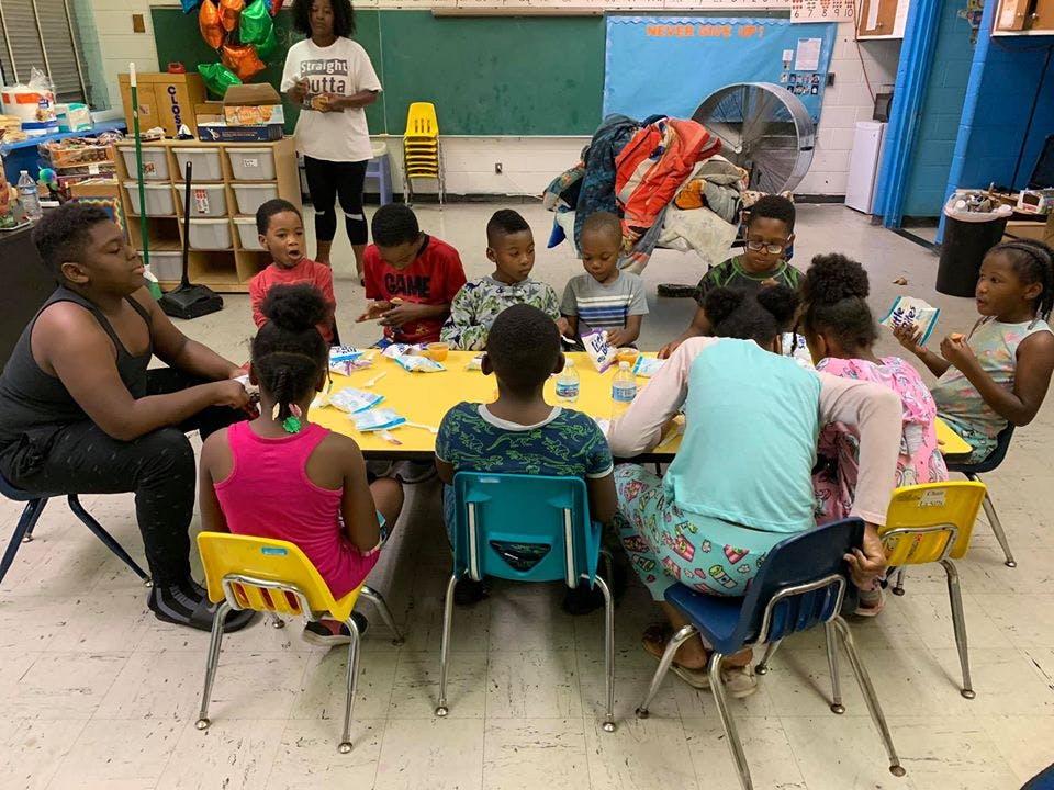Adults and children sitting around a yellow table in a classroom