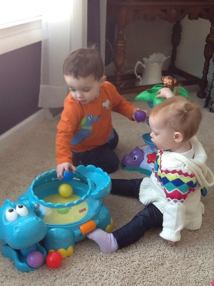 Two children playing with toys on a carpeted floor