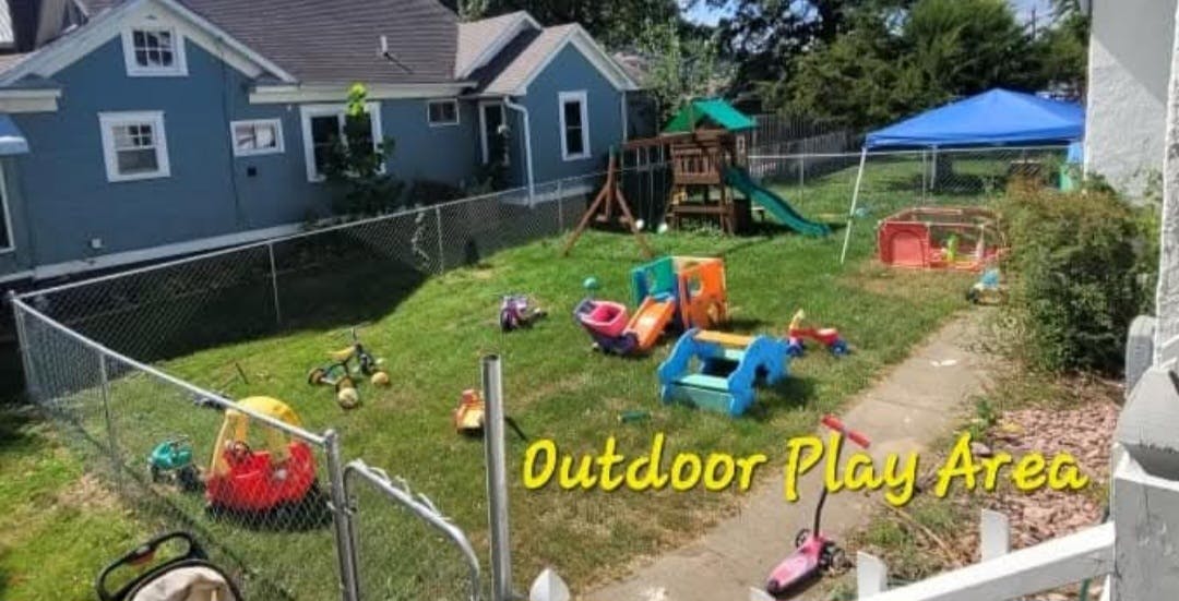 Outdoor play area with various toys and play structures in a fenced yard