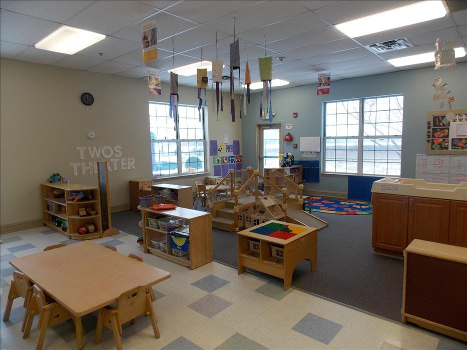 An empty early childhood classroom with play structures, tables, and toys