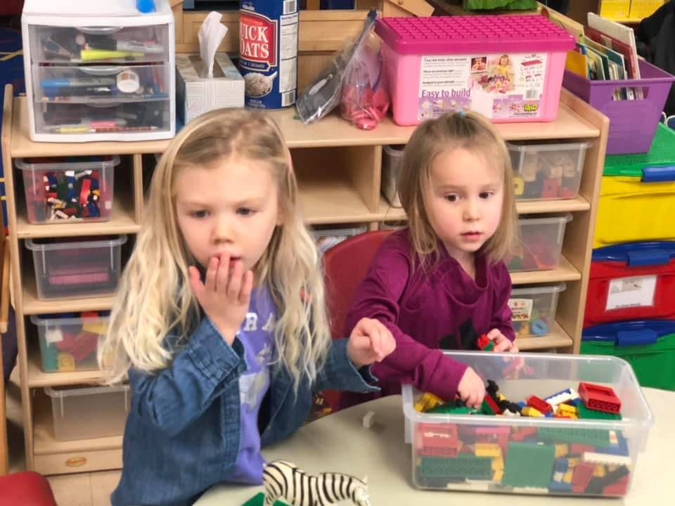 Two children playing with building blocks in a classroom