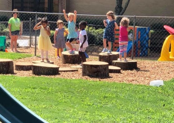 Children playing on tree stumps on a playground