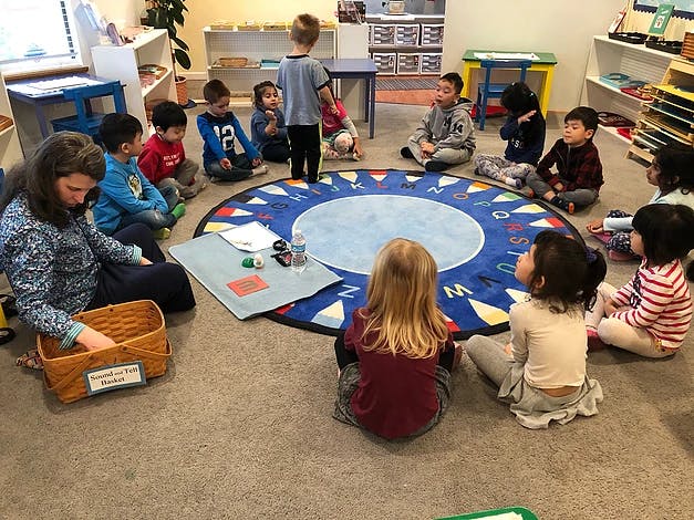 Adult and children sitting on a rug in a classroom