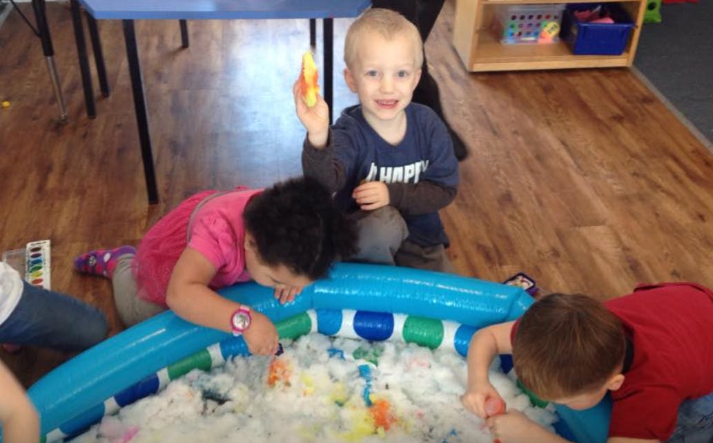Children playing in a sensory bin with foam and toys