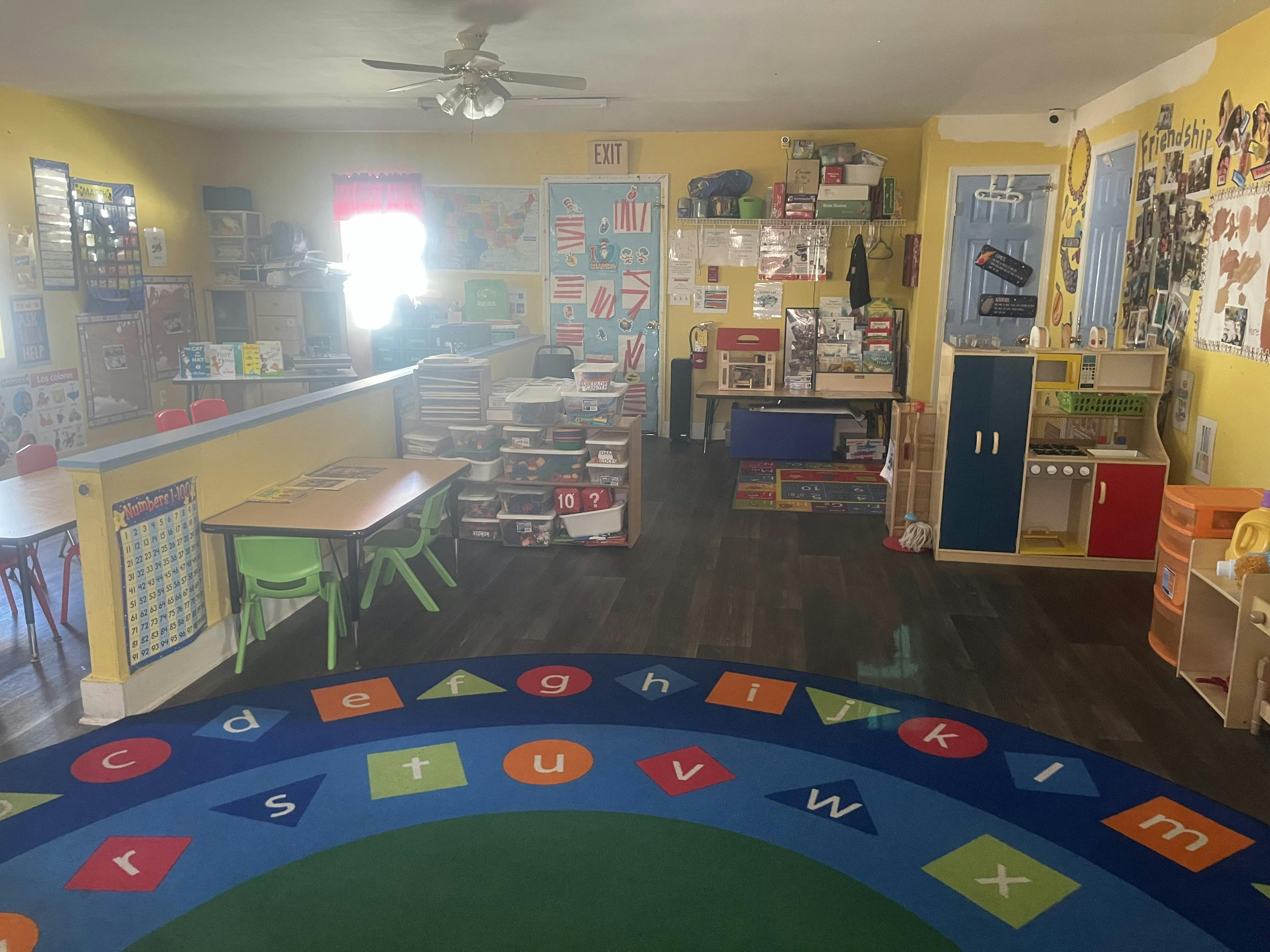 Playroom with an alphabet rug, small tables, and shelves of toys