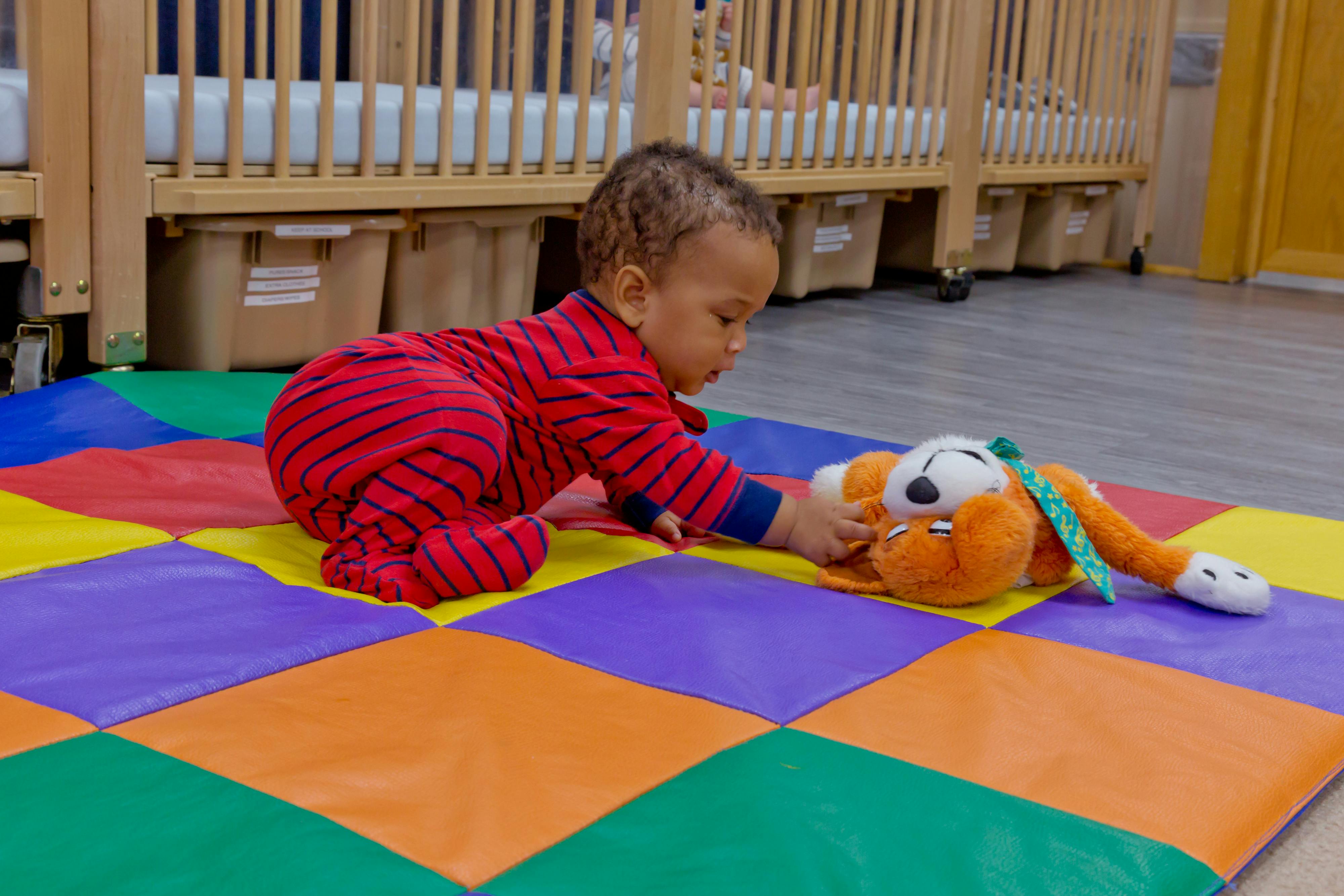 Child playing with a stuffed animal on a colorful mat