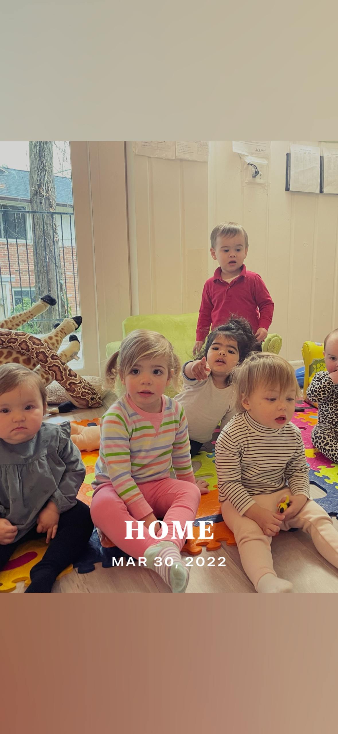 Multiple children sitting and standing on a colorful mat