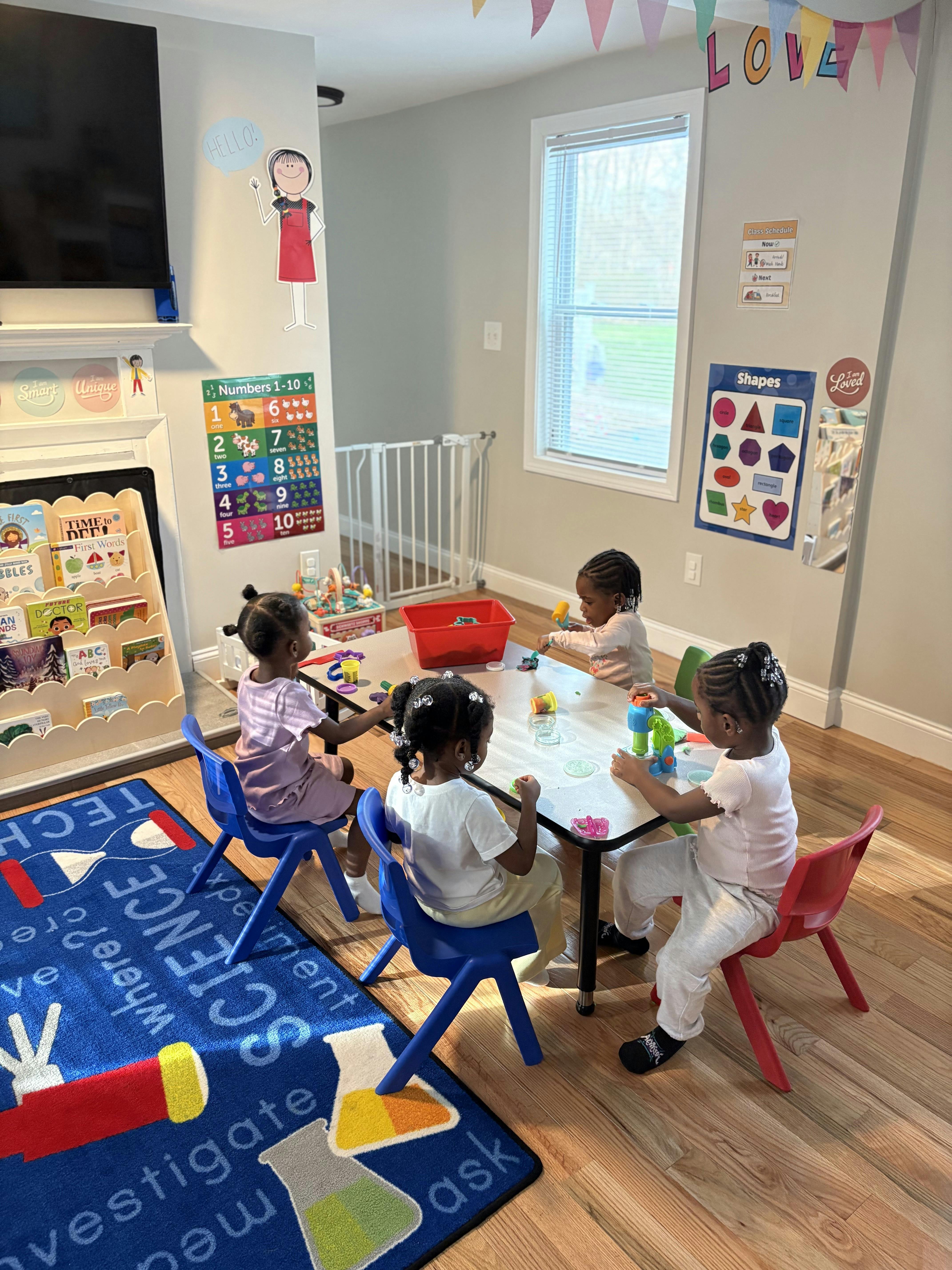 Four children sitting at a table playing with toys in a classroom