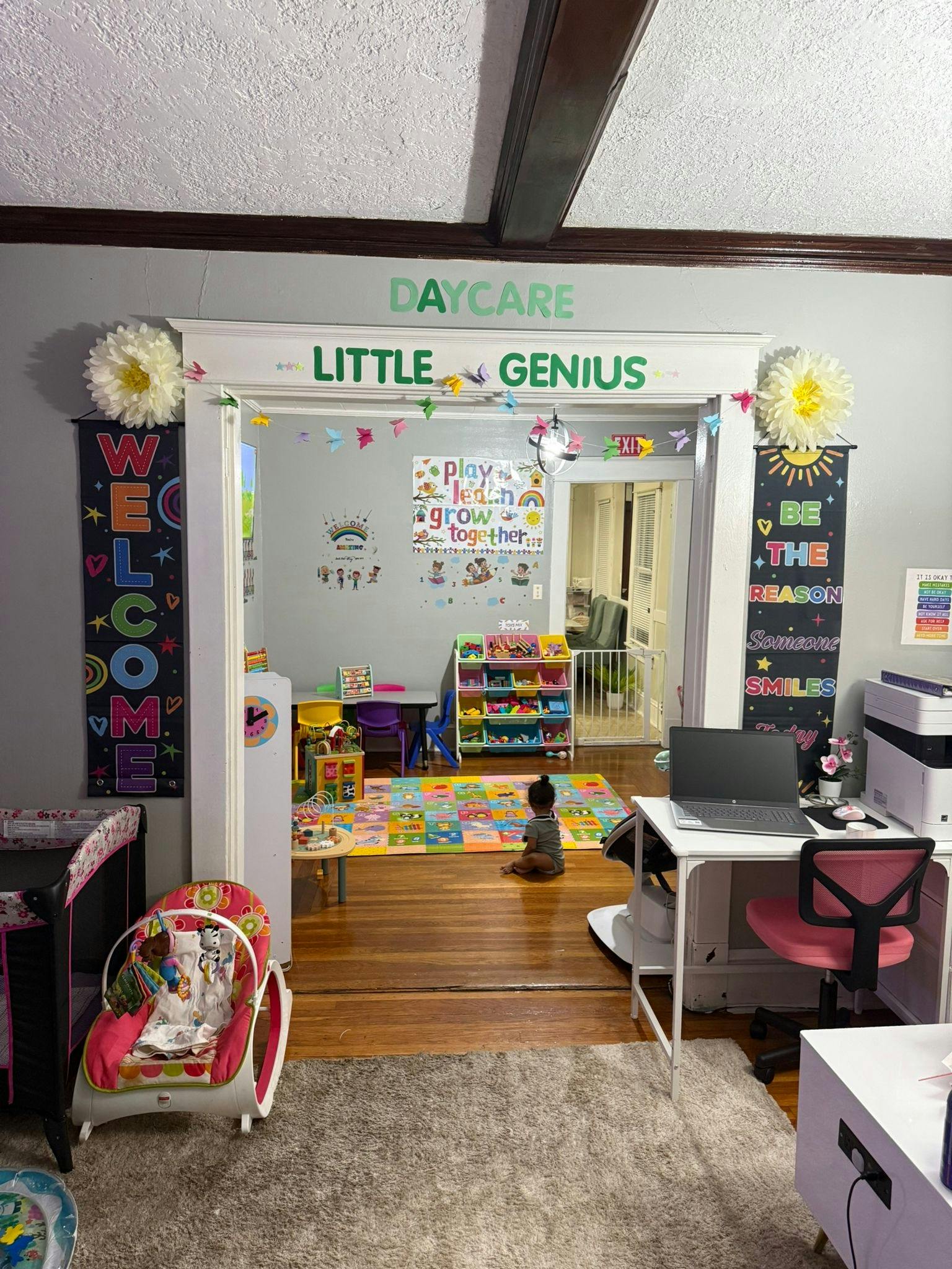 Daycare entrance with "Little Genius" sign and child on floor