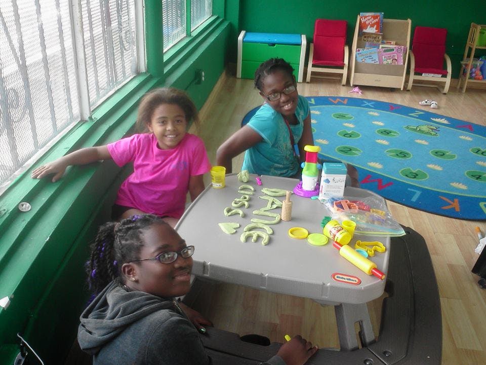 Three people at a table with playdough letters spelling "DANCE"