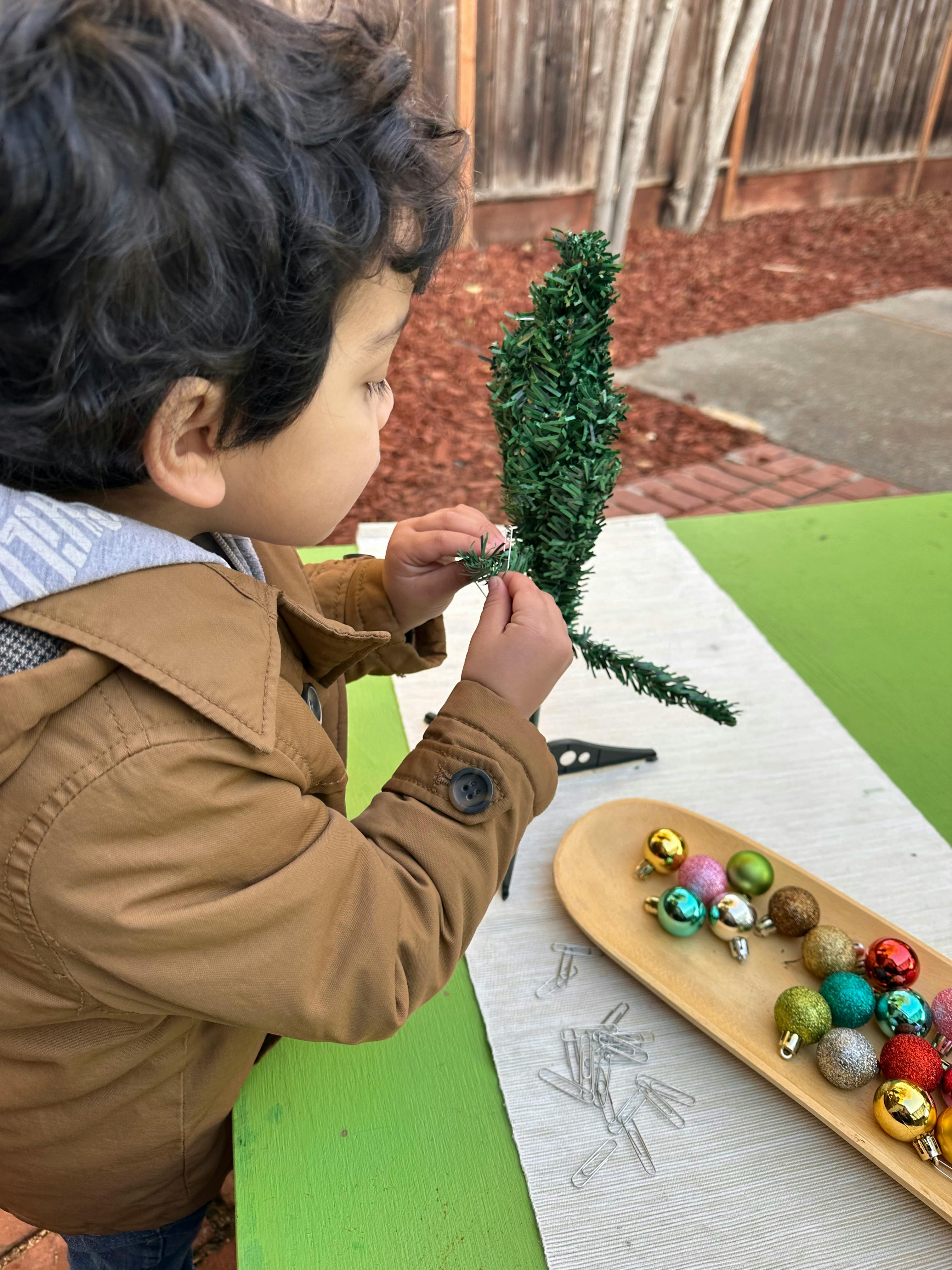 Child decorating a small artificial tree with ornaments