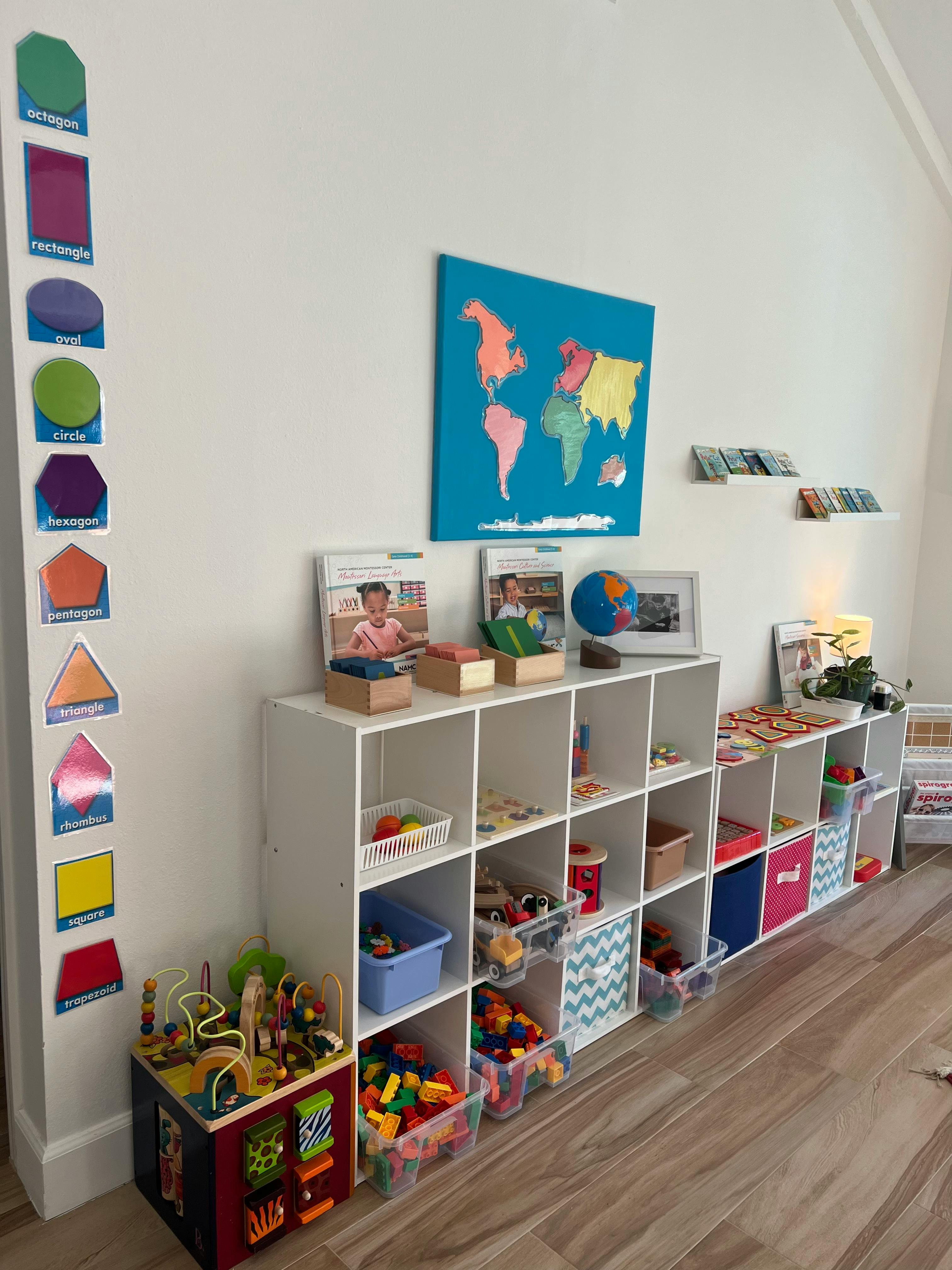 Wall with shape cutouts, world map art, and white cubby shelves with toys