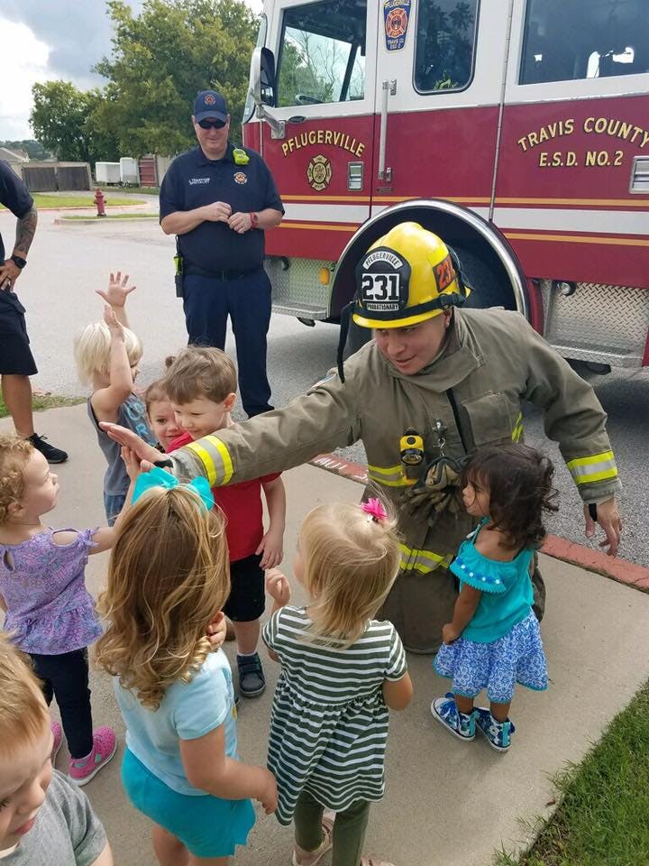 Firefighter kneeling and interacting with a group of children