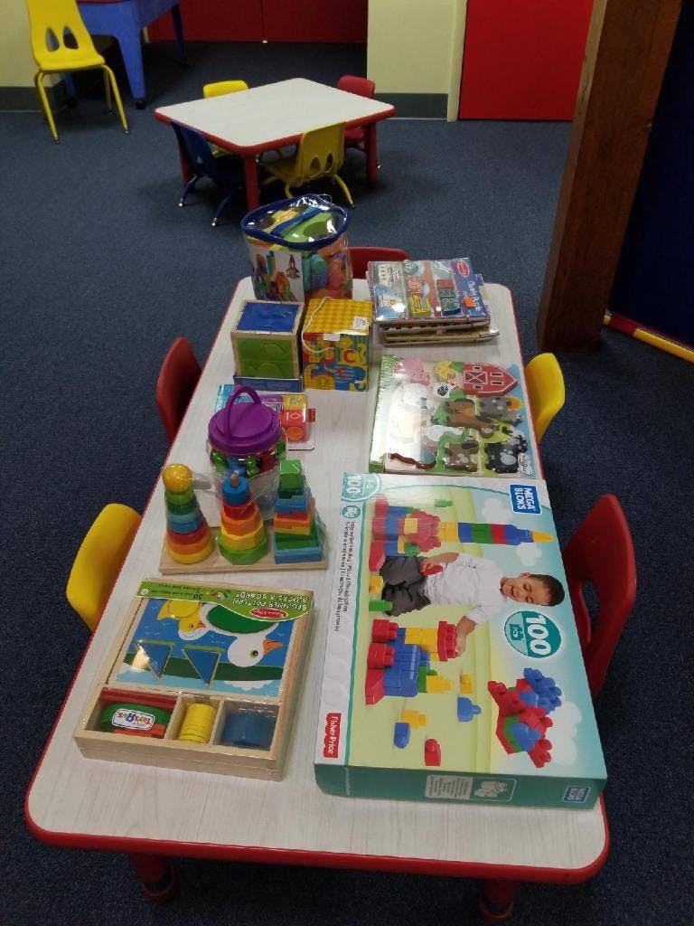 Table with various children's toys including blocks, puzzles, and stacking rings