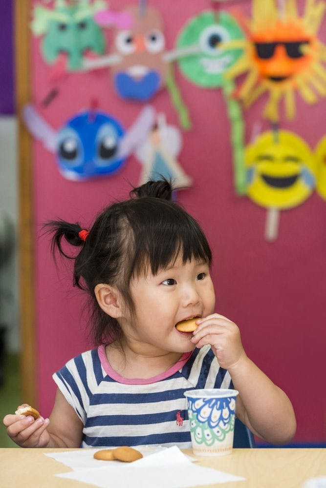 Child eating a cookie at a table