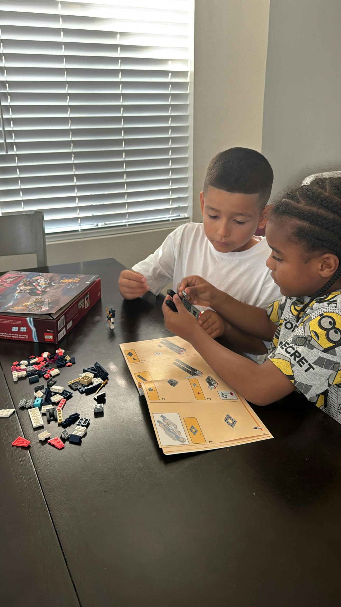 Two children building a toy set at a table
