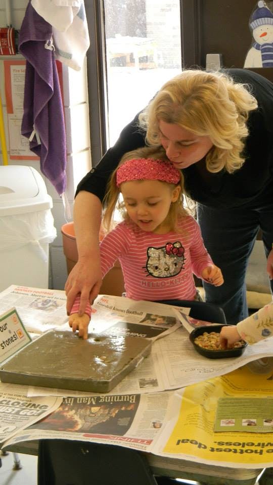 Adult and child making a craft with wet cement