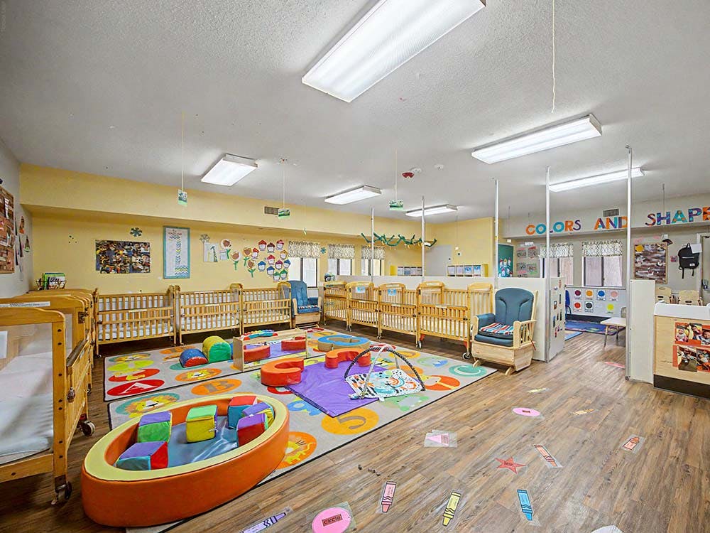 Cribs and colorful play mats in a child care room