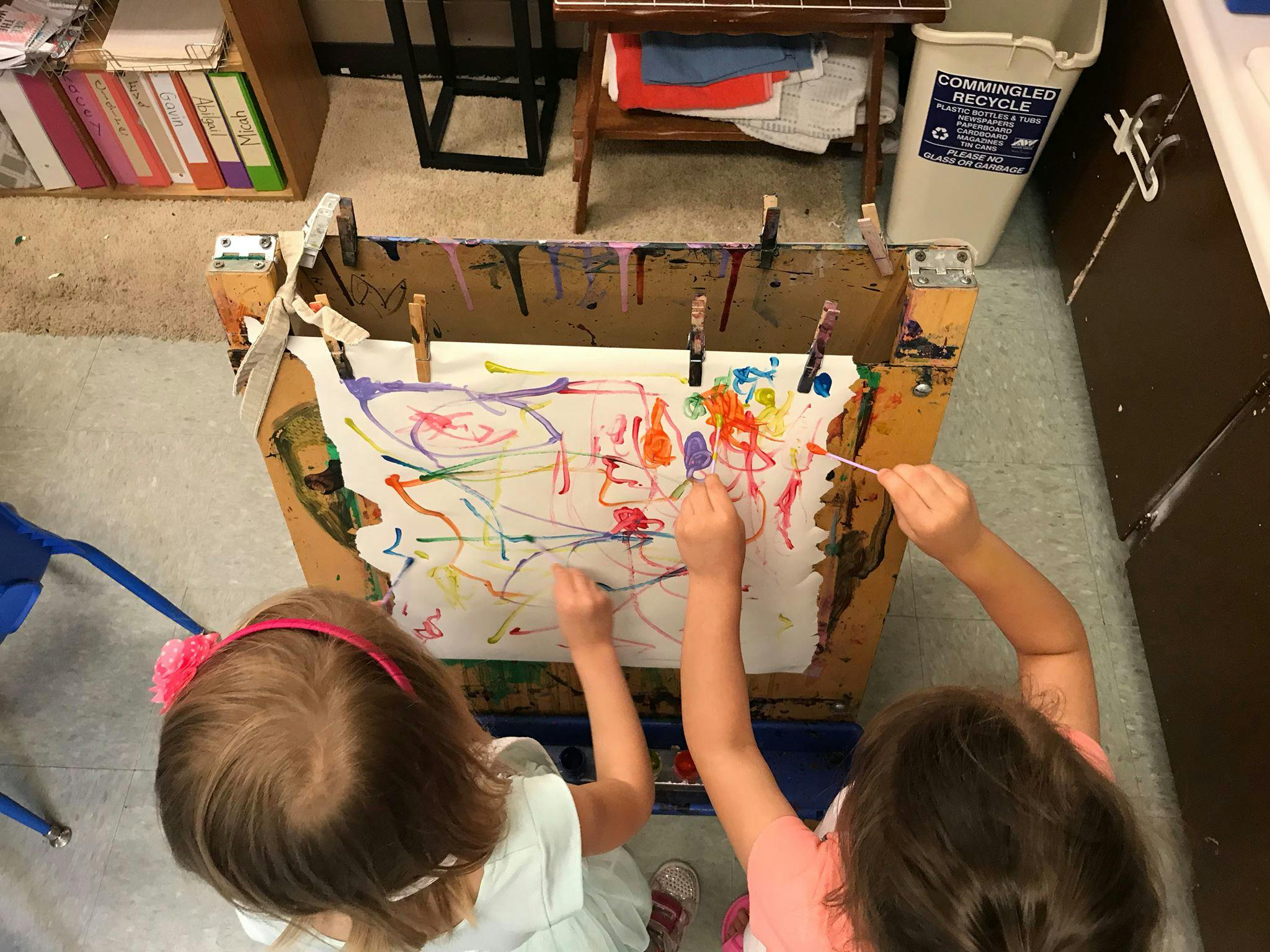 Two children painting on an easel
