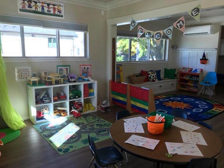 Playroom with toys, small table and chairs, and colorful rugs