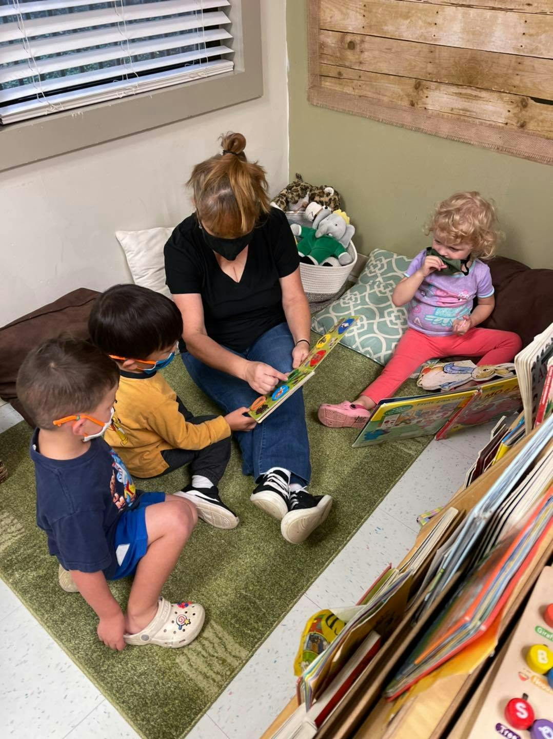 Person reading a book to two children in a classroom