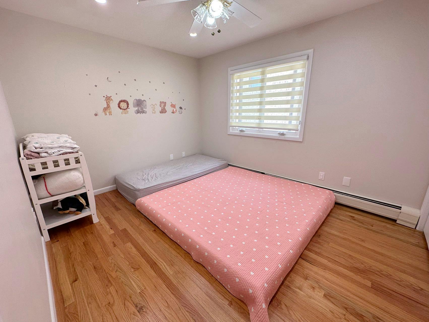 Bedroom with a pink mattress on the floor and a white changing table