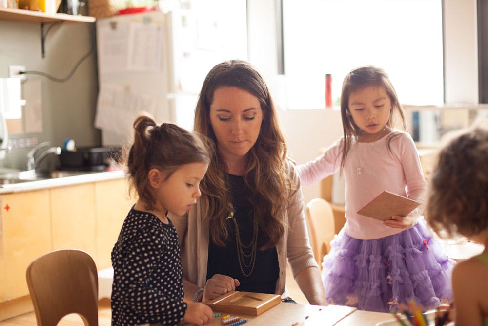 Adult and two children looking at an object on a table