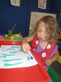 Child painting on paper at a table