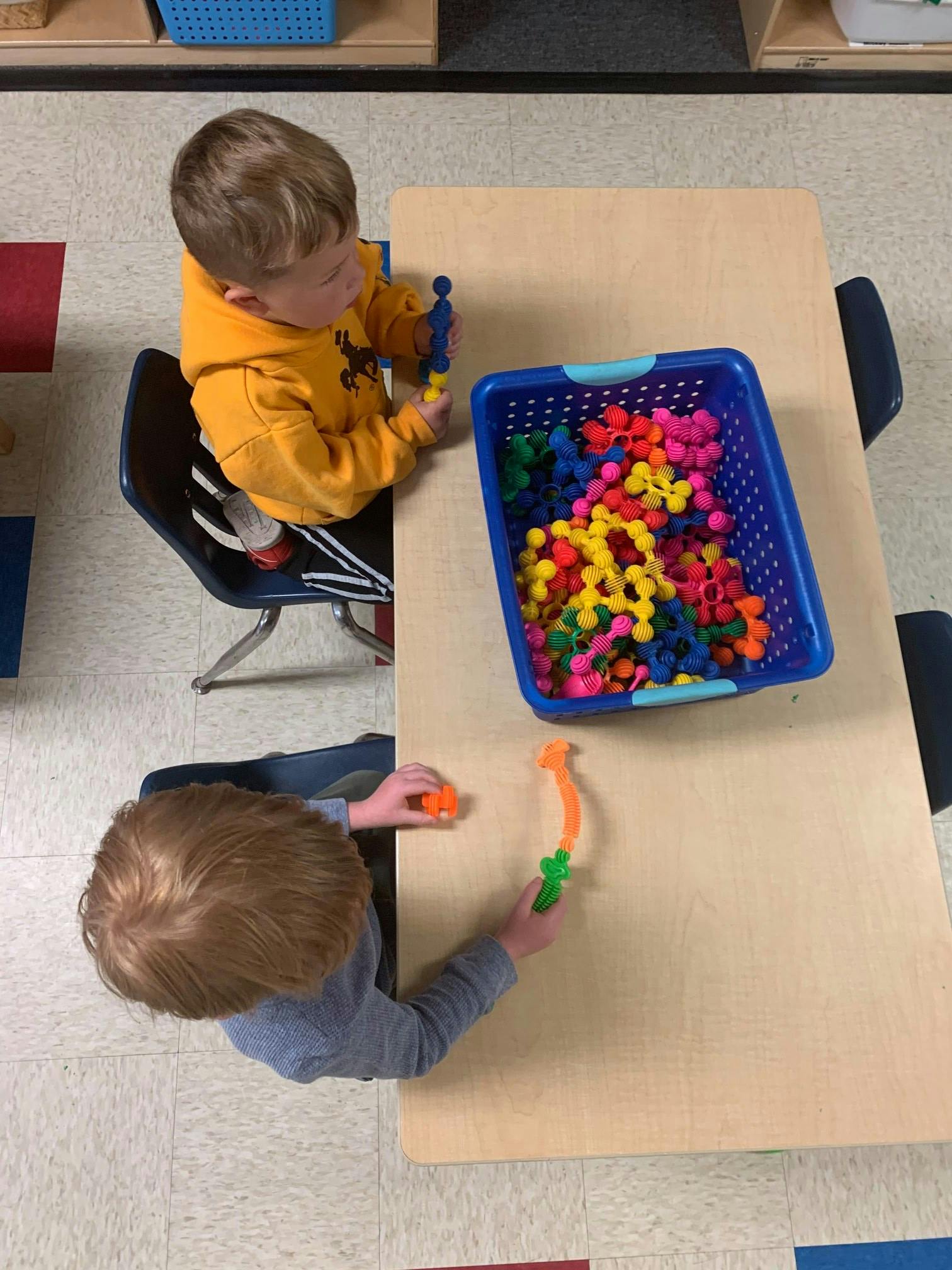 Two children playing with colorful building toys at a table
