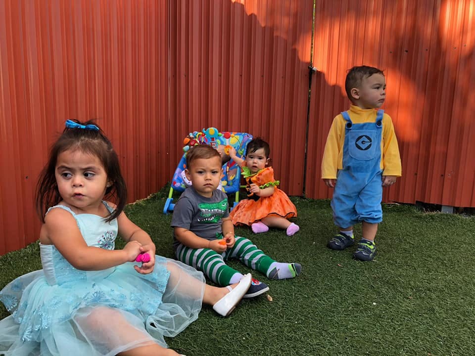Four children sitting and standing on grass